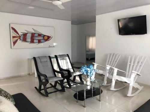 una sala de estar con sillas y una mesa con un pez en la pared en Mi Paraíso de Playa Blanca, en San Antero