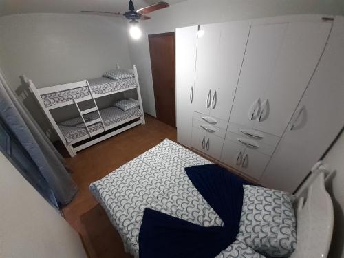 a small bedroom with a bed and a crib at Apartamento 100 metros da Praia Grande/Ubatuba/SP in Ubatuba