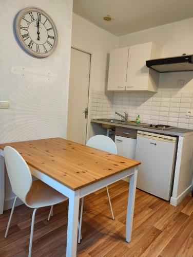 a kitchen with a wooden table and a clock on the wall at Avranches - gare- Mont Saint-Michel in Avranches