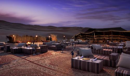 a desert setting with couches and tables in the desert at Anantara Qasr al Sarab Desert Resort in Jurayrah