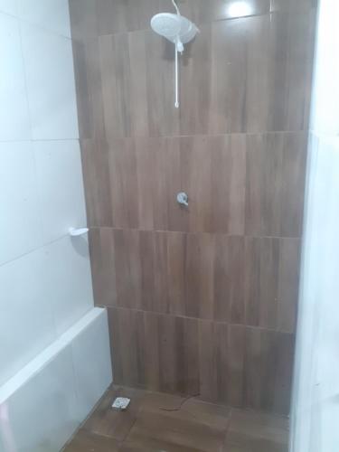 a bathroom with a shower with a wooden wall at Hospedagem da barra suites,praia barra grande,caminho de moises e antunes in Maragogi