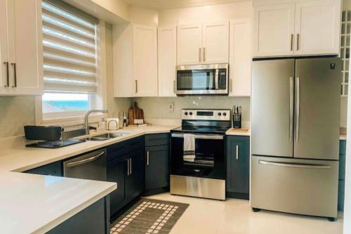 a kitchen with white cabinets and stainless steel appliances at Apartamento Vacacional en Montego Bay Jamaica in Kingston