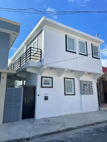 uma casa branca com uma varanda numa rua em 1058 Modern Apt 7 em San Juan