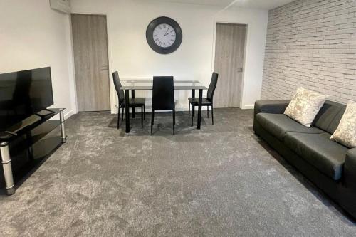 a living room with a couch and a table and a clock at 5. Homely Cecil Apartments in Birmingham