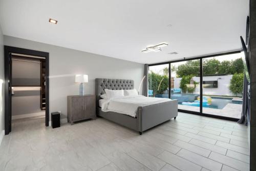 a white bedroom with a bed and a large window at Luxury Villa 5mins to Old Town w Pool Fire pit and BBQ in Scottsdale