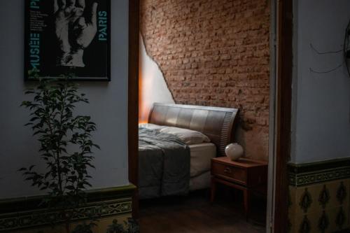 a bedroom with a couch and a brick wall at Casa Mutante Hostel in Montevideo