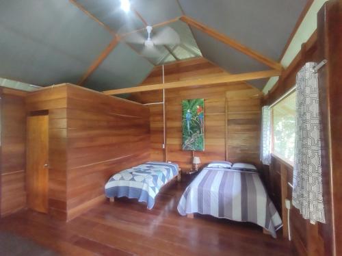 2 łóżka w pokoju z drewnianymi ścianami w obiekcie Quirquincho House w mieście Puerto Maldonado