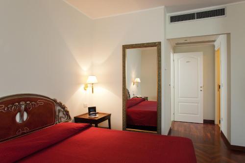 una camera con letto rosso e specchio di Hotel Villa Pigna ad Ascoli Piceno