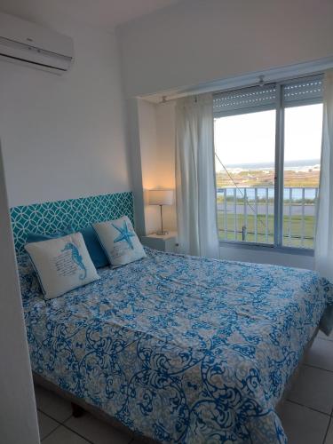 1 dormitorio con cama con colcha azul y ventana en Punta Mar en Mar del Plata