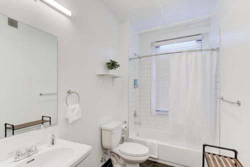 a white bathroom with a toilet and a sink at Modern Apartment in Historic Shell in Memphis