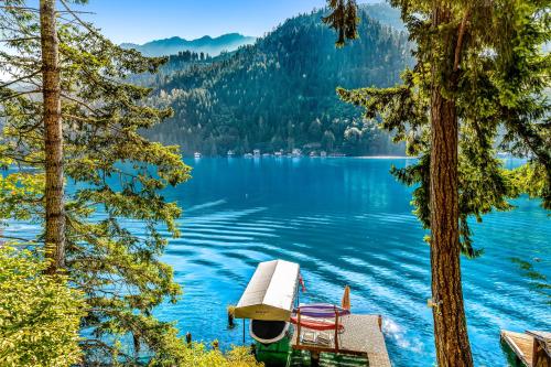 a view of a lake with a bench and chairs at Eagle's Nest on Lake Sutherland in Port Angeles