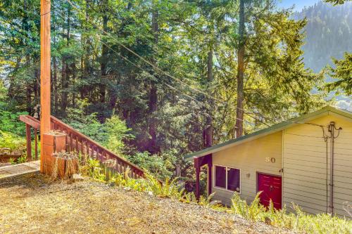 a small building with a red door next to a forest at Eagle's Nest on Lake Sutherland in Port Angeles