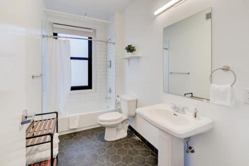 a white bathroom with a toilet and a sink at Historic Apartment in Prime Location in Memphis