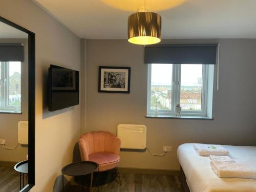 Zimmer mit einem Bett, einem Stuhl und einem Fenster in der Unterkunft Phoenix Pods in Liverpool