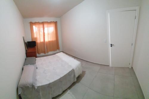 Habitación blanca con cama y puerta en Casa nova 2 quartos 1 garagem Morretes, en Itapema