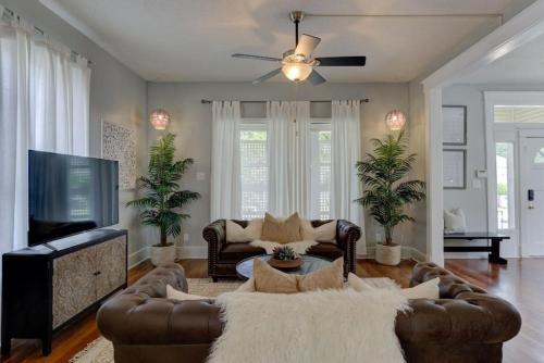 a living room with couches and a flat screen tv at Walk to Overton Square from your Historic Retreat in Memphis