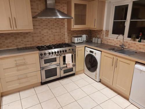 a kitchen with a stove and a washing machine at Luxury 4 bed house in Swindon in Swindon