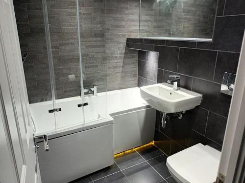 a bathroom with a sink and a tub and a toilet at Luxury 4 bed house in Swindon in Swindon