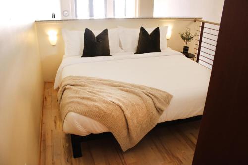 a bedroom with a large white bed with black pillows at NEW! Lavish Studio Loft in Central Downtown SLC in Salt Lake City
