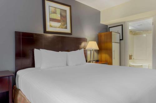 a bedroom with a large white bed and a bathroom at Best Western Plus Brooklyn Bay Hotel in Brooklyn