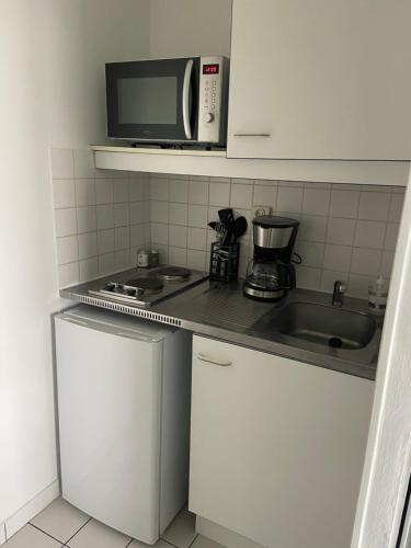 a kitchen with a microwave and a stove and a sink at Grand Studio Lumineux Caen Memorial in Caen
