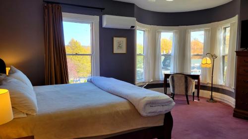 a bedroom with a bed and a desk and windows at The Elizabeth Inn and Restaurant in Bethel