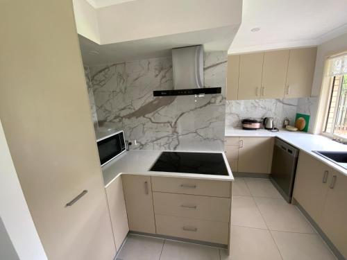 a kitchen with white cabinets and a marble wall at Shared house with other guests near shopping center and theme parks in Gold Coast