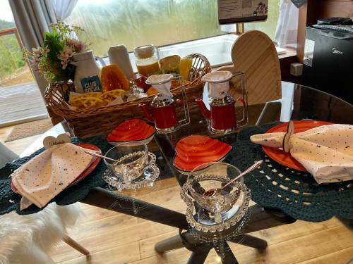 a glass table with food and drinks on it at Cabana Romântica Anitápolis/SC in Annitapolis