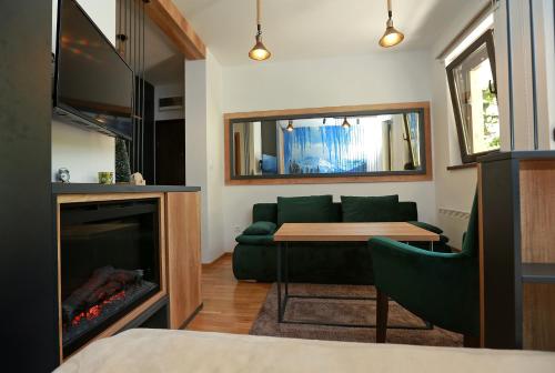 a living room with a green couch and a fireplace at Apartman KUTAK Jahorina in Jahorina