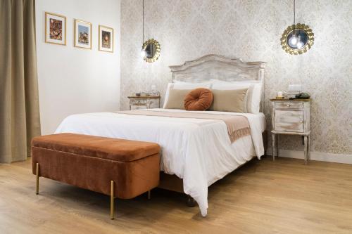 a bedroom with a large white bed with a brown ottoman at Lugar do Ourives Boutique Hotel in Senhora das Febres
