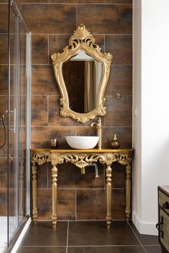 a bathroom with a gold mirror on a wooden wall at Lugar do Ourives Boutique Hotel in Febres