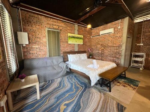 uma sala de estar com um sofá e uma parede de tijolos em Rembulan Escape - The Red Bowl em Kampung Penarik