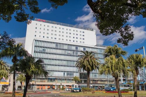 a white building with palm trees in front of it at JR Kyushu Hotel Miyazaki in Miyazaki