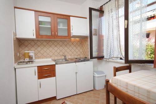 une petite cuisine avec des placards blancs et une table dans l'établissement Apartments and rooms with parking space Porec - 6917, à Poreč