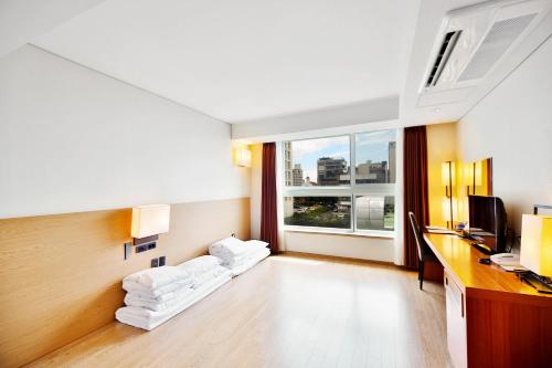 a hotel room with a desk and a window at Bareve Hotel in Seogwipo