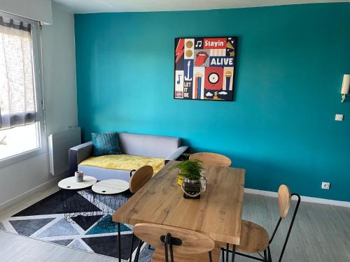 un salon avec une table et un mur bleu dans l'établissement Grand Studio Lumineux Caen Memorial, à Caen