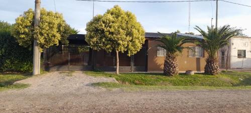 a house with two palm trees in front of it at Casa quinta ramallo in Ramallo
