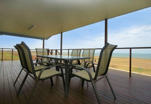 a table and chairs on a deck with a view of the beach at 17 Sea Esplanade in Elliott Heads