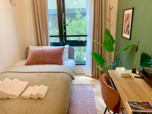 a bedroom with a bed and a desk and a window at Ken's Place四谷 in Tokyo