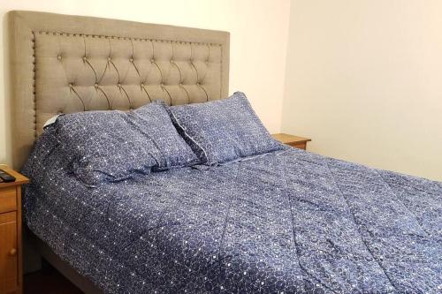 a bed with a blue comforter and pillows at Cómodo dpto centro de Santiago hasta 3 personas in Santiago