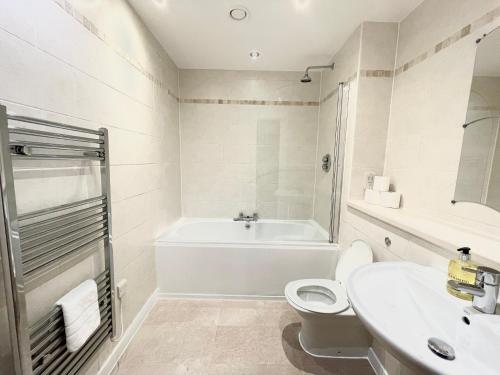 een badkamer met een bad, een toilet en een wastafel bij Lovely 2 - bedroom condo in Manchester City centre in Manchester