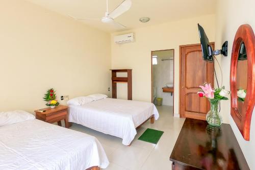 a hotel room with two beds and a vase of flowers at Hotel las flores in Santa Cruz Huatulco