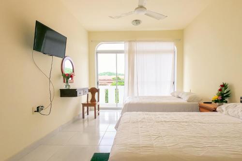 um quarto com 2 camas, uma televisão e uma janela em Hotel las flores em Santa Cruz, Huatulco