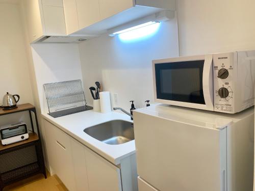 a kitchen with a sink and a microwave on a counter at Ken's Place四谷 in Tokyo
