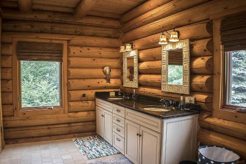 ein Blockhausbad mit einem Waschbecken und 2 Spiegeln in der Unterkunft Enjoy this stunning Log home with open floor plan and tons of natural lighting Ridgetop in Killington