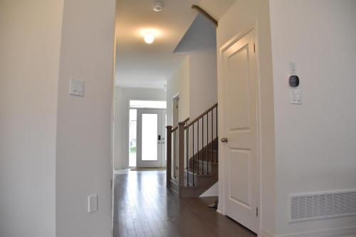 an empty hallway with a white door and a staircase at PARADISE VILLa Bowmanville in Bowmanville
