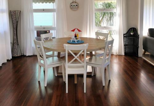 - une table à manger avec des chaises blanches et une table en bois dans l'établissement 115 Esplanade, à Bargara