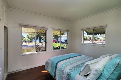 a bedroom with a bed and two windows at 115 Esplanade in Bargara