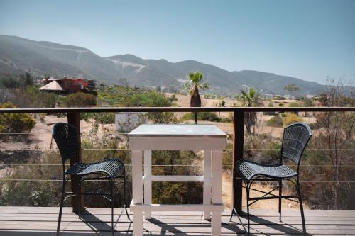 a white table and two chairs on a deck with a view at Viña Calabria in Valle de Guadalupe