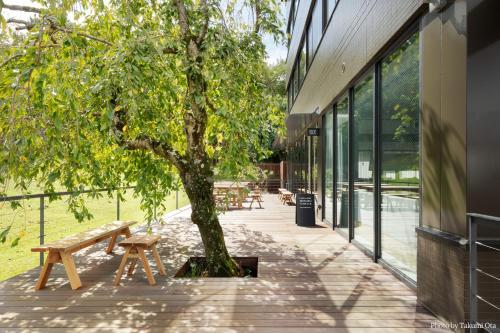 a tree in front of a building with a bench at MIROKU NARA by THE SHARE HOTELS in Nara